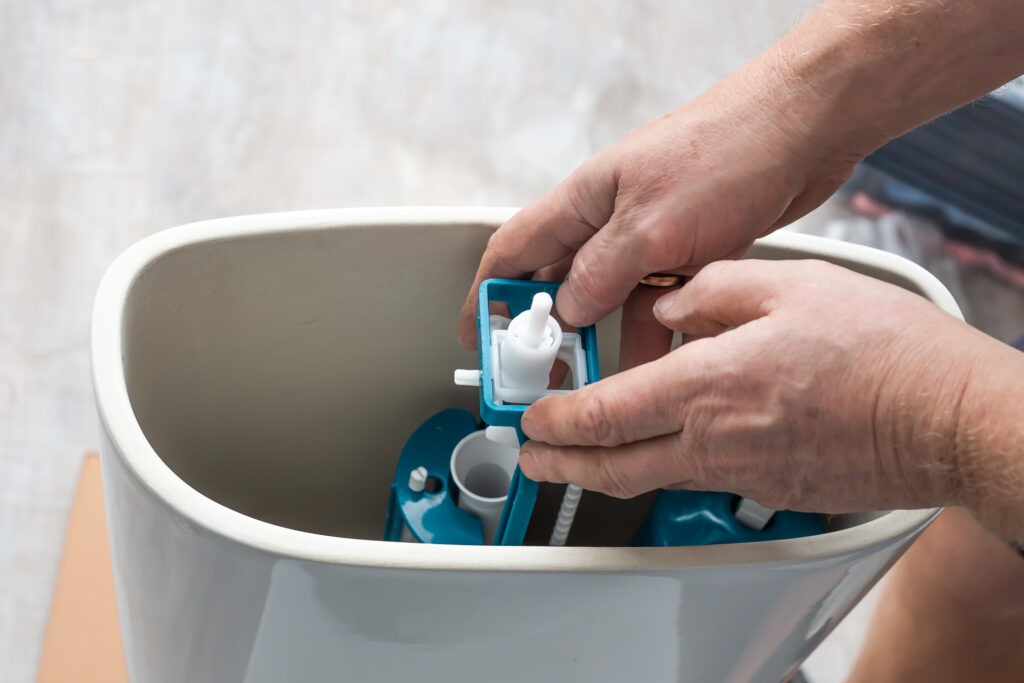 Plumber replacing pump in toilet