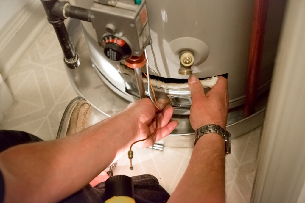 Man working on a hot water heater in a dark closet