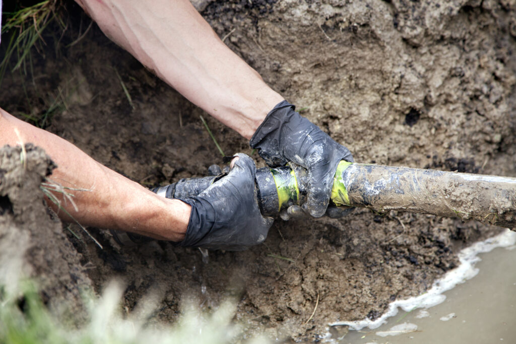 Plumber working on a sewer line in a yard